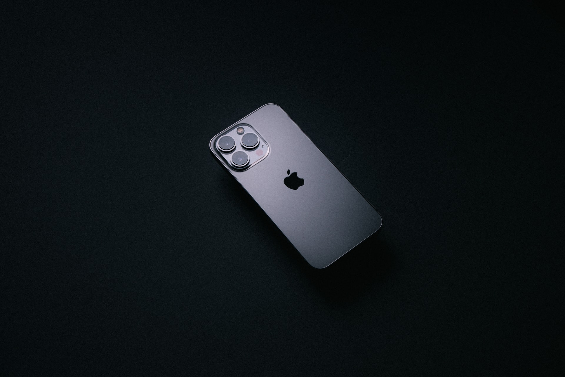 Shadowy photo of a grey iPhone 13 Pro Max in the dark