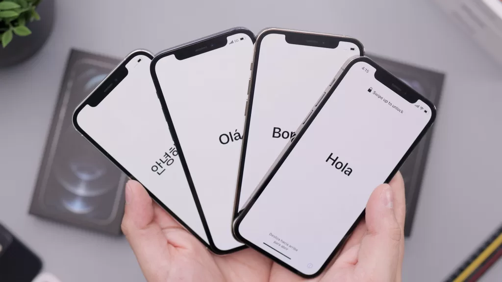 Photo of hands holding 4 iPhones, of which all of them are at the page of early setup. All in different language